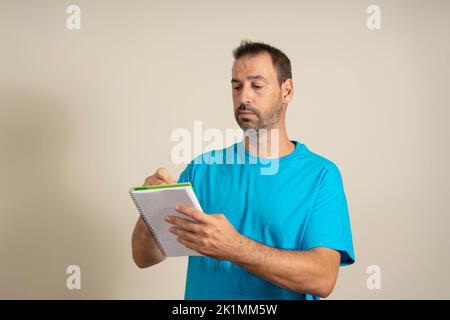 Primo piano ritratto del suo bello attraente allegro cheery Dreamy bearded ragazzo tenendo in mano copybook creazione di strategia isolata sul colore beige Foto Stock