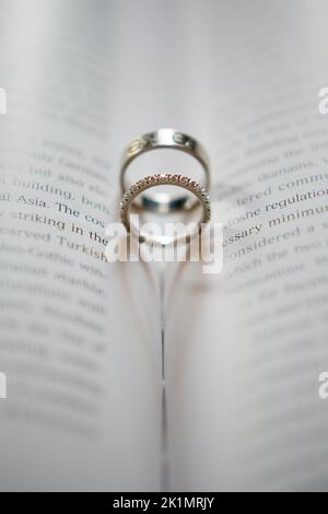 Gli anelli di nozze della sposa e delle sale bilanciati all'interno della spina dorsale di un libro Foto Stock