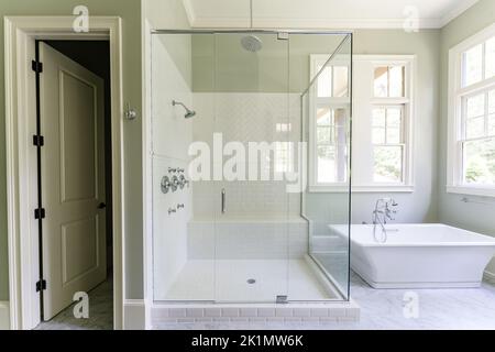 Bagno verde salvia con finiture bianche dover, vasca indipendente, doccia chiusa con vetro con mattoni a spina di pesce dipinti in bianco, piano di granito Foto Stock
