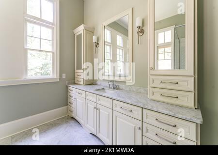 Bagno verde salvia con finiture bianche dover, vasca indipendente, doccia chiusa con vetro con mattoni a spina di pesce dipinti in bianco, piano di granito Foto Stock