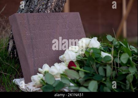 Saarlouis, Germania. 19th Set, 2022. I partecipanti al rally commemorativo per il richiedente asilo ghanese Samuel Yeboah, ucciso in un attacco di arson nel 1991, hanno deposto fiori in una pietra commemorativa. A metà novembre, il processo contro un uomo di 51 anni inizierà presso la Corte superiore regionale di Coblenza, con accuse, tra cui omicidio. Si presume che abbia acceso il fuoco nella sistemazione dei richiedenti asilo la notte tra il 18 e il 19 settembre 1991, a Saarlouiser Strasse. Credit: Harald Tittel/dpa/Alamy Live News Foto Stock