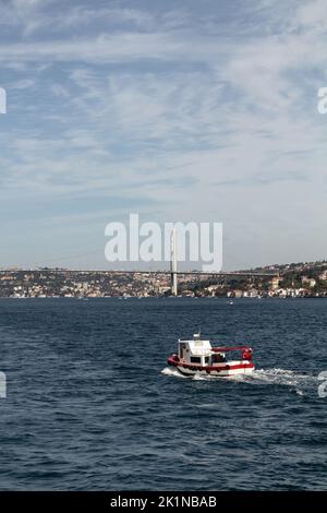 Vista di una piccola e tradizionale barca da pesca sul Bosforo e sul ponte di Istanbul. E' una giornata estiva di sole. Foto Stock