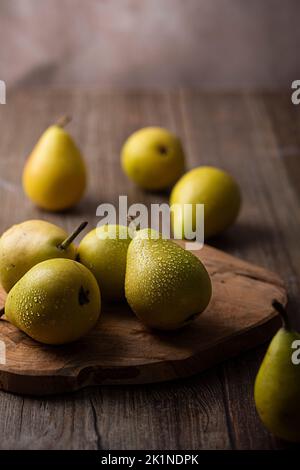 Pere fresche su un asse di legno con gocce d'acqua sulla buccia Foto Stock