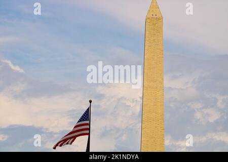 Vista nel tardo pomeriggio del Washington Monument, accanto a una bandiera americana che sventola in una brezza moderata nel luglio 2022 Foto Stock