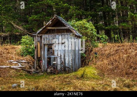 Abbandonata capanna nelle Highlands scozzesi con una vecchia bici arrugginita Foto Stock