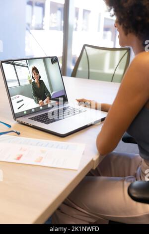 Videoconferenza biracial businesswoman con il collega sul laptop in ufficio Foto Stock