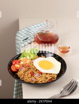 Indomie Goreng, il marchio più popolare Instant Noodle dall'Indonesia. Servito con verdure e uova lato sole Foto Stock