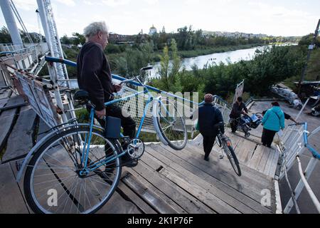 Izium, Ucraina. 19th Set, 2022. Persone che trasportano biciclette attraverso il ponte nella città di Izium, recentemente liberata dalle forze armate ucraine, nella regione di Kharkiv. La città di Izium fu occupata dalle truppe russe il 1 aprile 2022. Credit: SOPA Images Limited/Alamy Live News Foto Stock