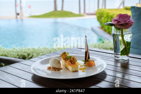 dessert con gelato al cocco e torta di mango su un piatto a bordo piscina. Dessert tropicale Foto Stock
