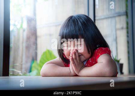 Felice bambina che prega a casa, fede pura del bambino Foto Stock