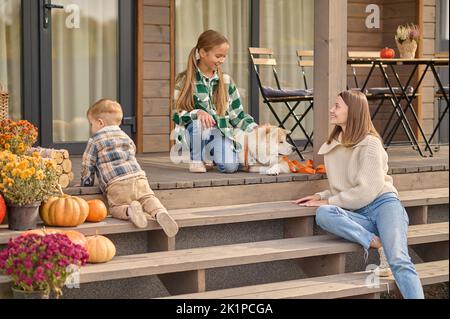 Genitore femmina che trascorre il tempo con i suoi figli sulla veranda Foto Stock