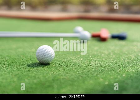 Putters e palle da golf in miniatura assortiti si inclinano su erba sintetica. Foto Stock