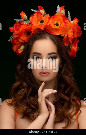 Una bella donna Ucraina che indossa una colorata corona nazionale di papaveri rosso scarlatto. Indirizzo della ragazza. Fermare la guerra in Ucraina. Foto di alta qualità Foto Stock