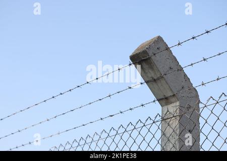 Filo spinato e cielo blu sullo sfondo Foto Stock