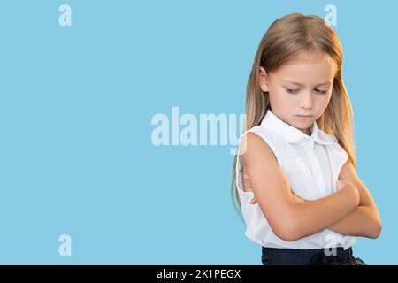 Bambino pensivo. Sentimenti feriti. Bullismo scolastico. Ritratto di troubled pensuroso bambina triste in vestito formale in piedi con le braccia ripiegate guardando verso il basso io Foto Stock