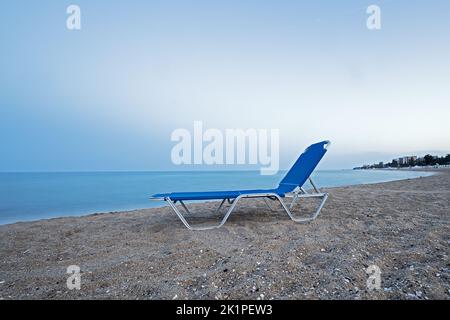 poltrona blu inutilizzata sulla spiaggia Foto Stock