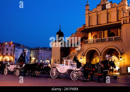 Cracovia, carrozze polacche di fronte alla sala dei tessuti rinascimentali nella città vecchia o Rynek Glówny, piazza del mercato medievale. Foto Stock