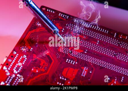 Un uomo che salda una scheda madre. Riparazione e manutenzione di personal computer desktop e laptop. Foto Stock