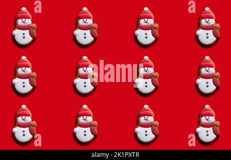 Sfondo rosso di Natale. Modello Snowman. Decorazioni per le vacanze invernali. Simpatico divertente biscotto di pan di zenzero composizione festiva per i bambini isolato su brillante senza cuciture Foto Stock