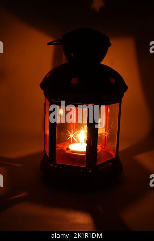 Incenso bruciatore censitore con fumo e sfondo bianco. Ornamentale lanterna araba con candela incandescente in mano. Foto Stock