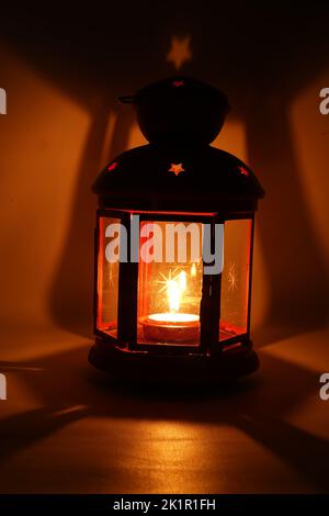 Incenso bruciatore censitore con fumo e sfondo bianco. Ornamentale lanterna araba con candela incandescente in mano. Foto Stock