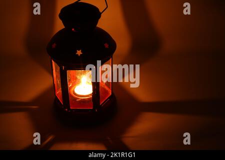 Incenso bruciatore censitore con fumo e sfondo bianco. Ornamentale lanterna araba con candela incandescente in mano. Foto Stock