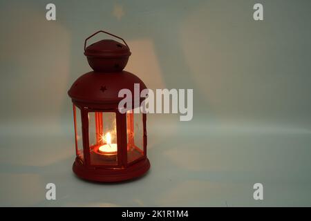 Incenso bruciatore censitore con fumo e sfondo bianco. Ornamentale lanterna araba con candela incandescente in mano. Foto Stock