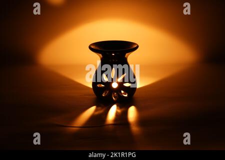 Incenso bruciatore censitore con fumo e sfondo bianco. Ornamentale lanterna araba con candela incandescente in mano. Foto Stock