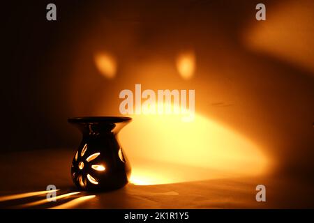 Incenso bruciatore censitore con fumo e sfondo bianco. Ornamentale lanterna araba con candela incandescente in mano. Foto Stock