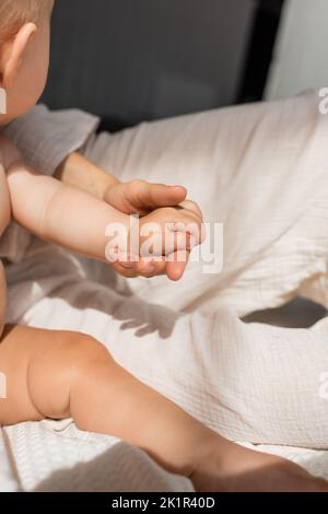 vista ritagliata della madre che tiene le mani con ragazza carina bambino in camera da letto, immagine stock Foto Stock