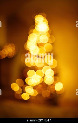 Luci bokeh dorate luminose a forma di albero di nuovo anno. Sfondo sfocato festivo Foto Stock