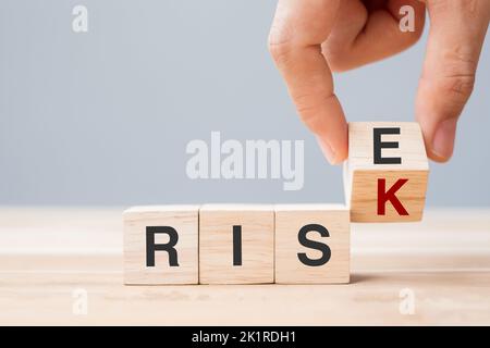 Mano d'affari che capovolgono i blocchi del cubo di legno con CAMBIAMENTO DI RISCHIO per AUMENTARE il testo sullo sfondo della tabella. Economico, probabilità, atteggiamento, opportunità e crisi con Foto Stock