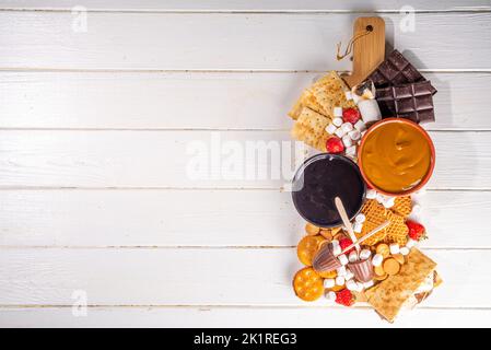 S'mores cibo e ingredienti per feste a casa. Buffet di base Smores con marshmallow vari, cracker, cioccolato, frutta, cioccolato, condimenti, salse. Foto Stock