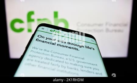 Telefono cellulare con sito web del Consumer Financial Protection Bureau (CFPB) sullo schermo davanti al logo. Messa a fuoco in alto a sinistra del display del telefono. Foto Stock