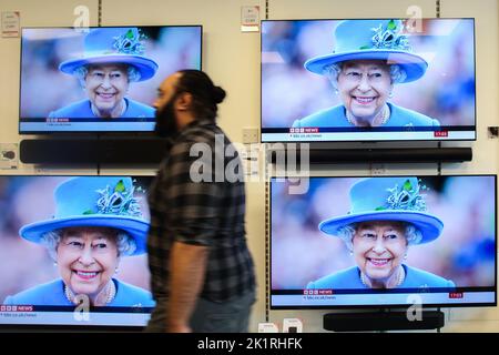 REGNO UNITO, Londra: 18th settembre 2022 Un uomo cammina sugli schermi televisivi in un negozio di elettricità a Kingston, Londra, riportando le notizie di Foto Stock