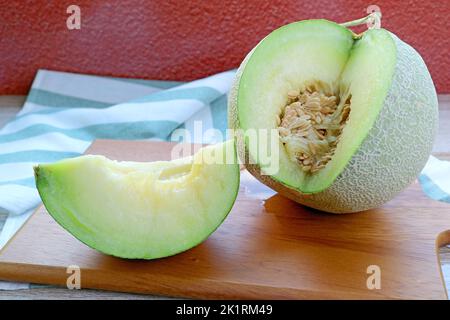 Muskmelon fresco maturo con una fetta Juicy taglio da frutta intera su tagliere di legno Foto Stock