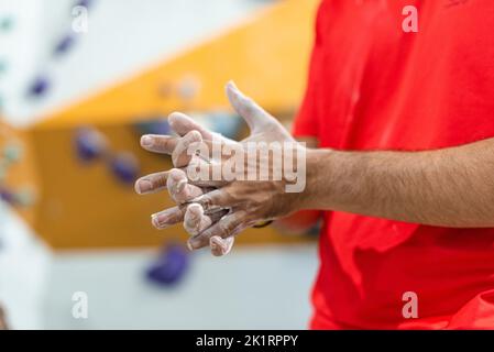 Uomo che stenderà magnesio liquido sulle sue mani per esercitarsi nella parete di arrampicata Foto Stock
