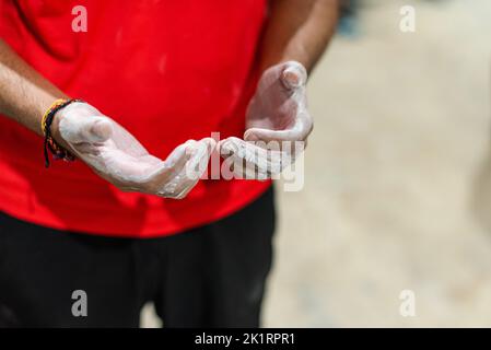Uomo che stenderà magnesio liquido sulle sue mani per esercitarsi nella parete di arrampicata Foto Stock