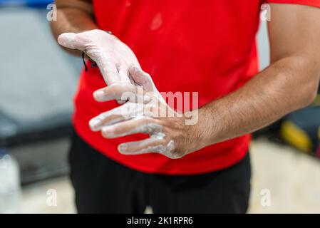 Uomo che stenderà magnesio liquido sulle sue mani per esercitarsi nella parete di arrampicata Foto Stock