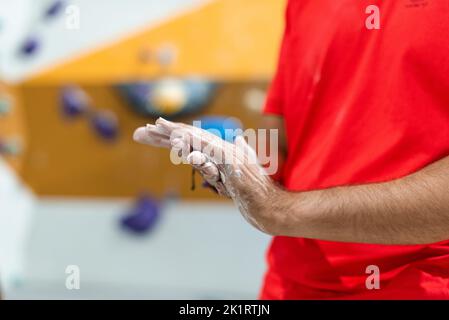 Uomo che stenderà magnesio liquido sulle sue mani per esercitarsi nella parete di arrampicata Foto Stock