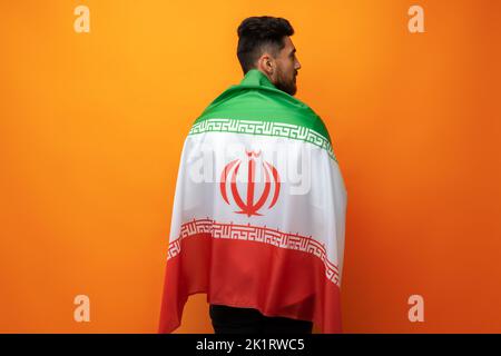 Ritratto di un giovane uomo casual con bandiera dell'Iran su sfondo arancione Foto Stock