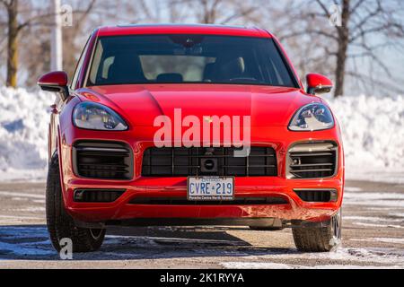 A Red Porsche Cayenne in un parcheggio basso in una giornata di sole durante l'inverno Foto Stock