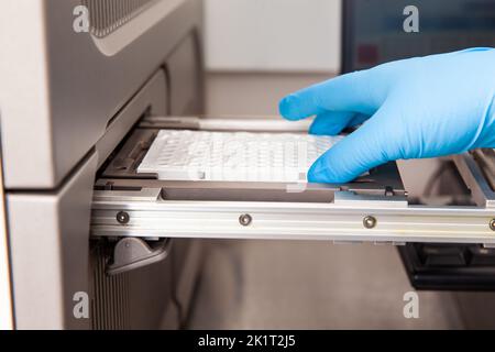 Lo scienziato carica i campioni in un termociclatore RT-PCR presso il laboratorio. Tecnica di reazione a catena della polimerasi in tempo reale. Tecnica RT-PCR Foto Stock