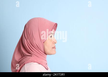 La donna del sud-est asiatico con hijab in piedi sullo sfondo blu Foto Stock