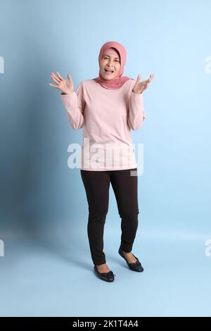 La donna del sud-est asiatico con hijab in piedi sullo sfondo blu Foto Stock