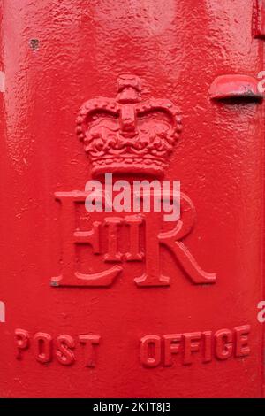 Primo piano di una tradizionale casella postale britannica rotonda rossa con una corona e le iniziali ER (Elizabeth - Regina) e il testo Post Office Foto Stock