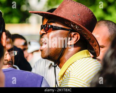 Londra Regno Unito Giugno 15 2009; uomo africano che indossa cappello e occhiali scuri con bocca aperta che chiama. Foto Stock