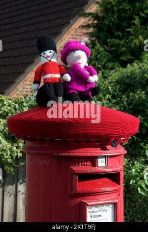 Un cappello in lana lavorato a mano, dai colori stravaganti, decora una tradizionale scatola di colonne rosse, celebrando il Giubileo del platino della Regina Elisabetta II 2022, REGNO UNITO. Foto Stock