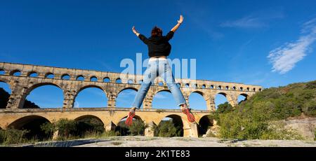 Donna che salta di fronte a Pont du Gard, Francia, Europa Foto Stock