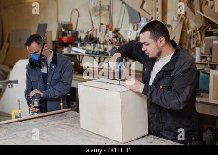 Ritratto di due lavoratori maschi che costruisce mobili in legno in officina fabbrica, copia spazio Foto Stock